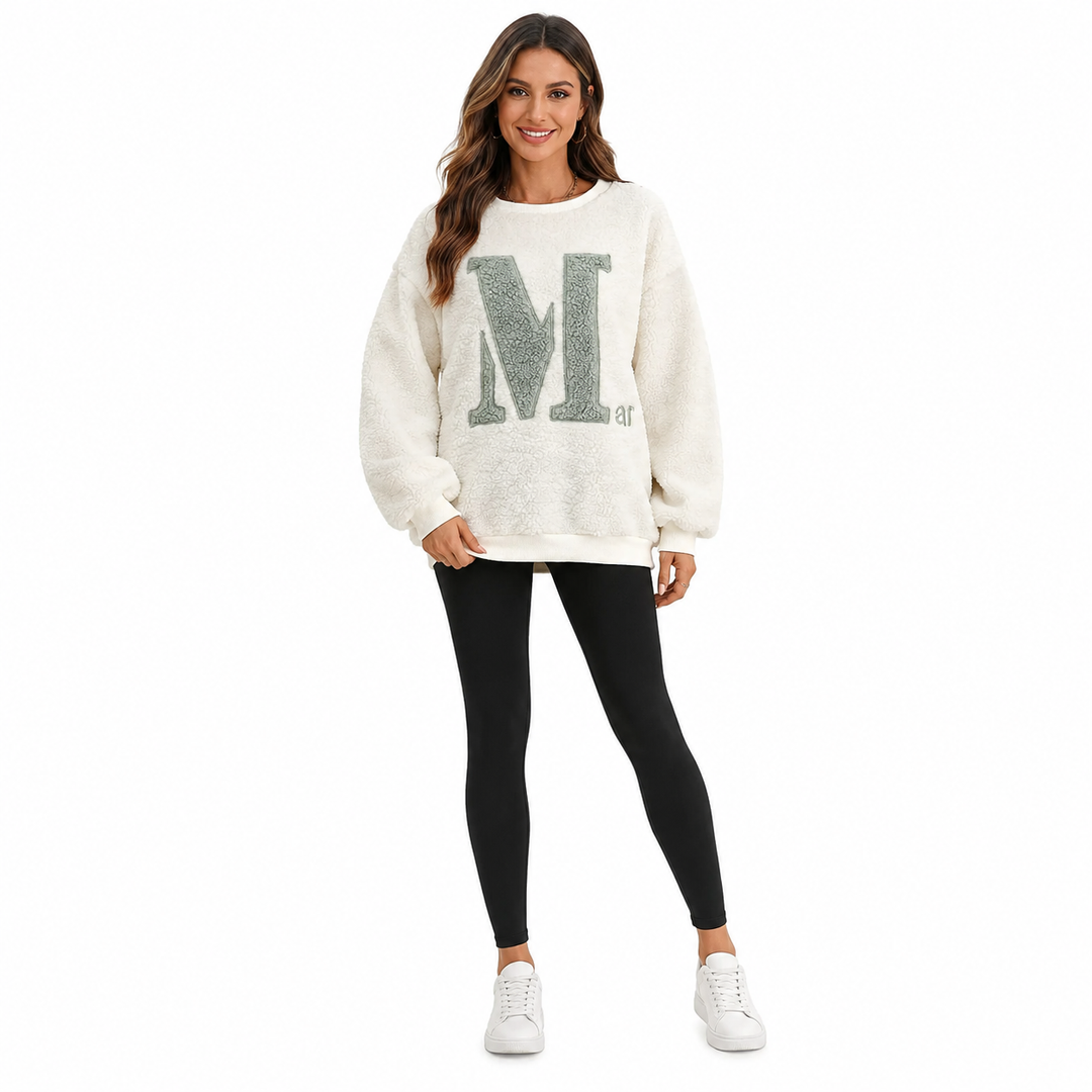 Woman wearing a white sweatshirt with a large letter &