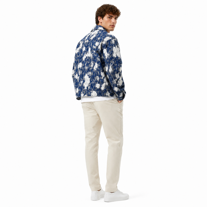 Man wearing a blue floral jacket and beige pants on a white background