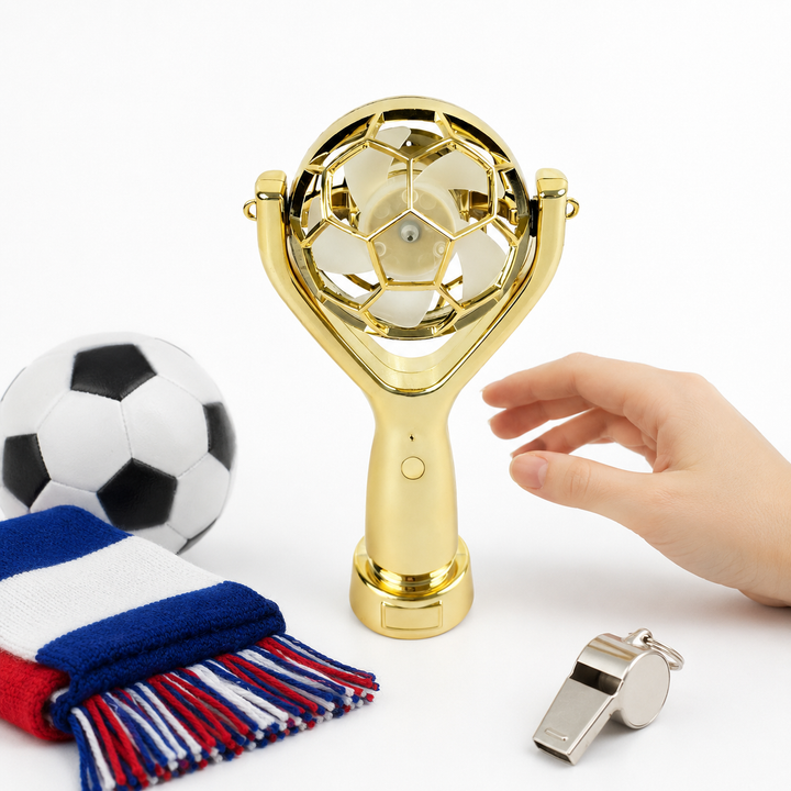 Compact handheld fan beside phone showing portable size, gold finish and match day accessory design for football fans now use