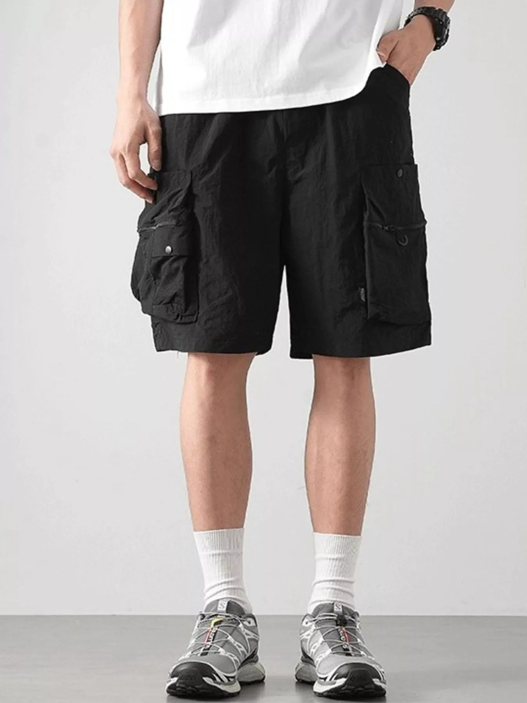 Person wearing black cargo shorts on a plain background