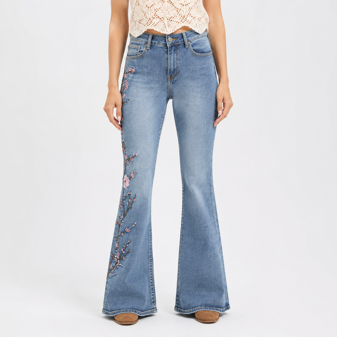 Flared jeans for women, light blue denim front view with high waist and pink floral embroidery along the outer leg, on white.