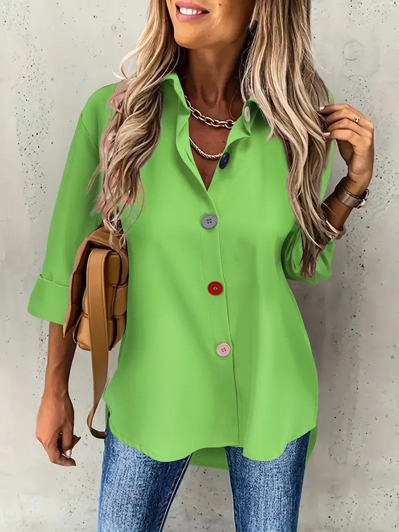 Woman wearing a bright green shirt with buttons, standing against a light gray wall.
