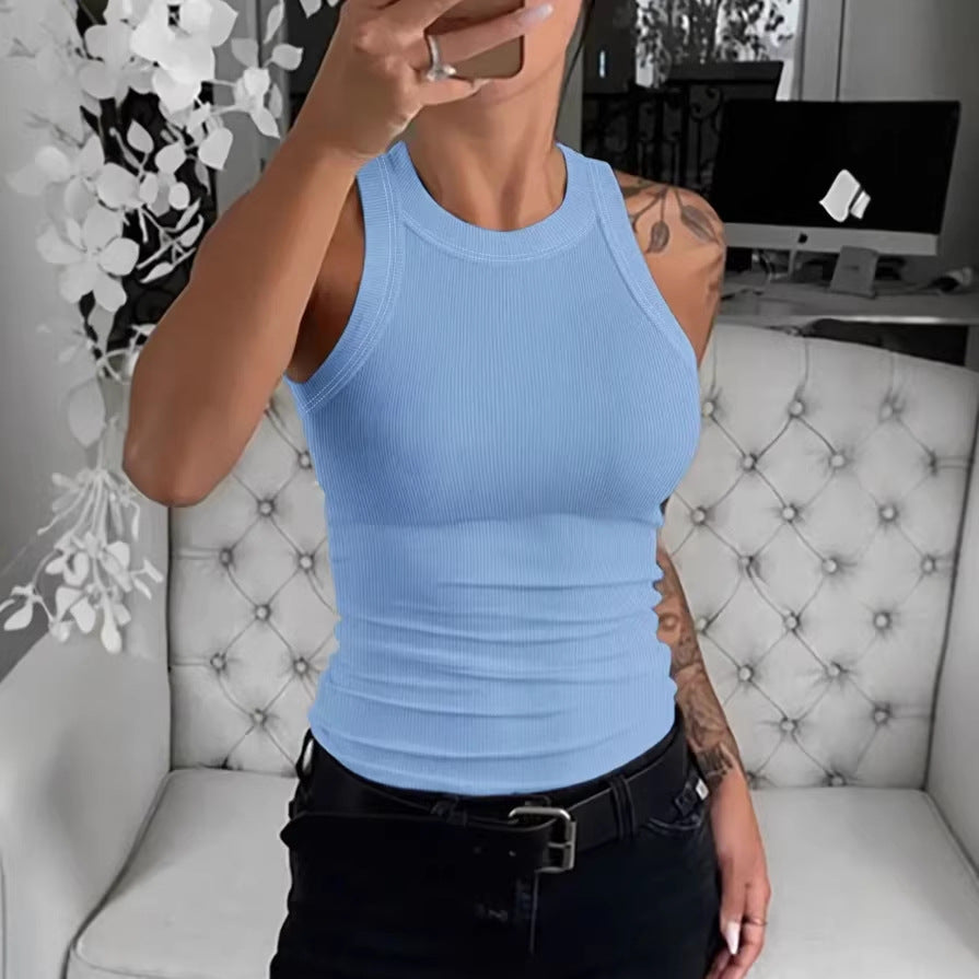 Person wearing a light blue tank top sitting on a white tufted chair.