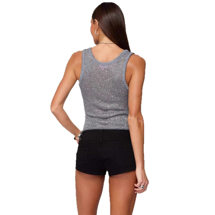 Woman wearing a sparkly gray tank top and black shorts on a white background