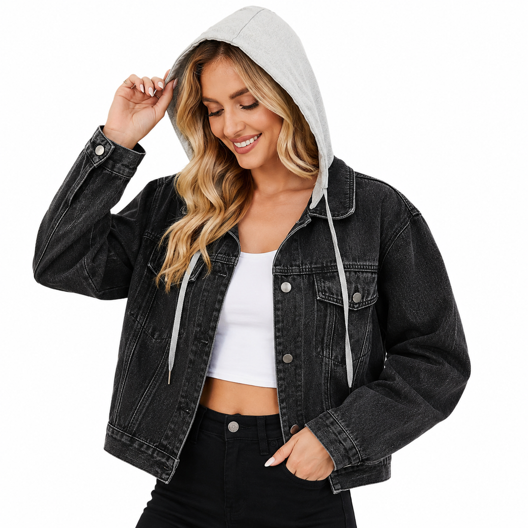 A woman wearing a black washed denim hooded jacket with a light gray hood and white drawstrings, layered over a white crop top and black pants, against a plain white background.