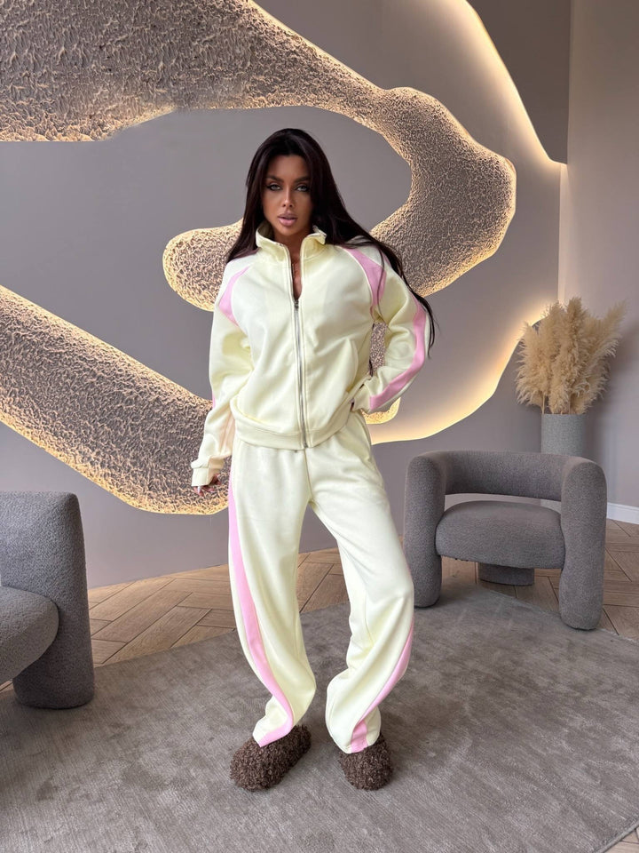 Person wearing a light-colored tracksuit with pink accents in a modern room.