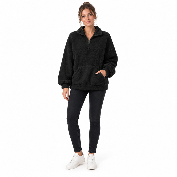 Black fleece pullover on a full-length adult model showing its front pocket, short zipper and stand collar in a white studio.