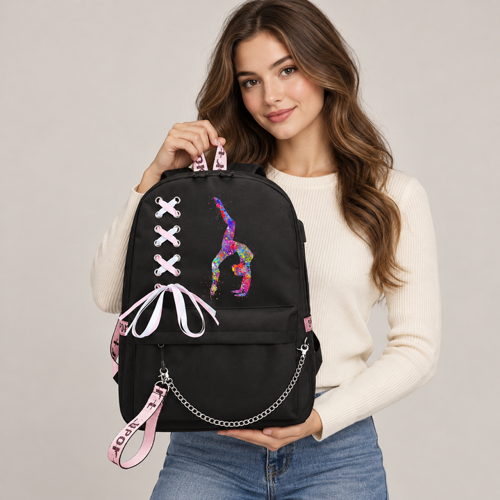 Model holding a black and pink backpack with handstand gymnast artwork, ribbon lacing and silver chain in a softly lit studio
