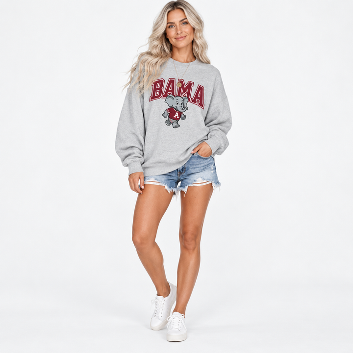Full-body studio view of female model wearing gray elephant-print sweatshirt and denim shorts