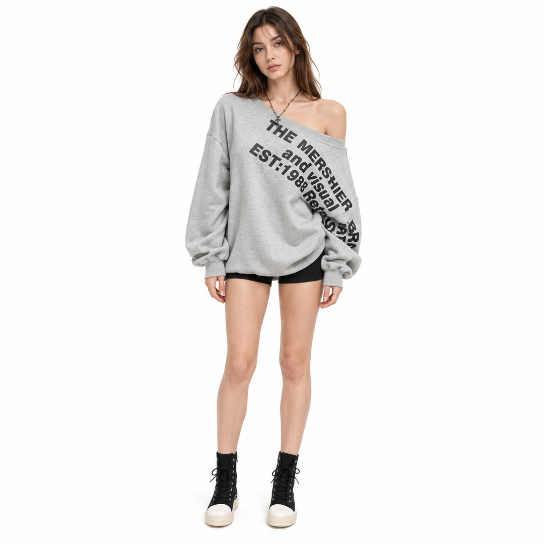 Front view of a woman in a grey sweatshirt with black lettering, long sleeves, black shorts and high-top shoes in the studio.