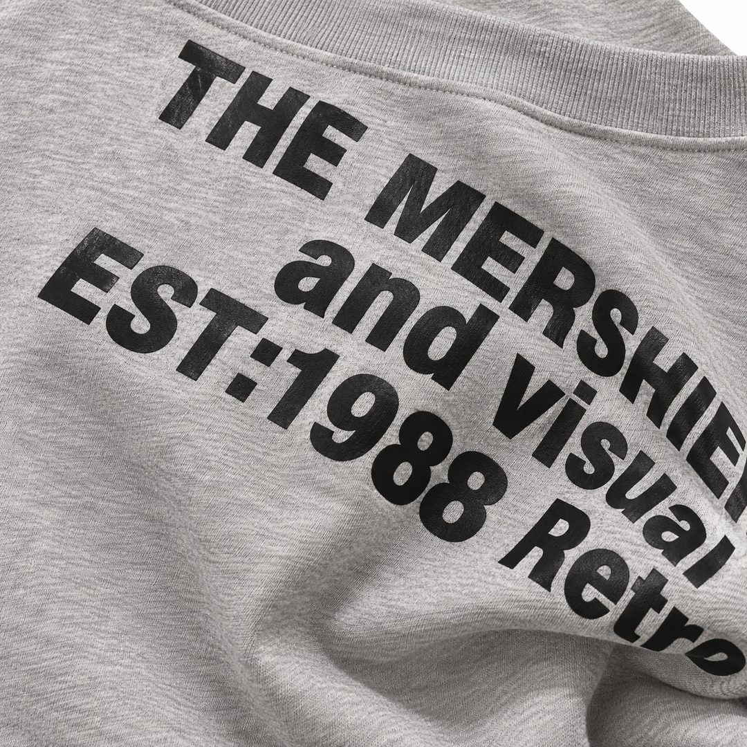 Close-up of black lettering on the heather grey sweatshirt, showing sharp print edges, grey surface and natural fabric folds.