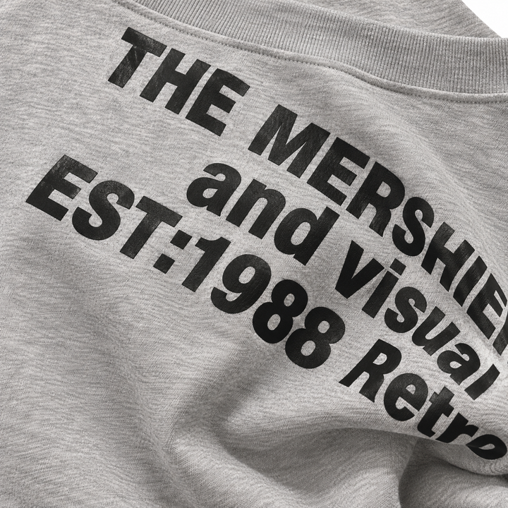 Close-up of black lettering on the heather grey sweatshirt, showing sharp print edges, grey surface and natural fabric folds.