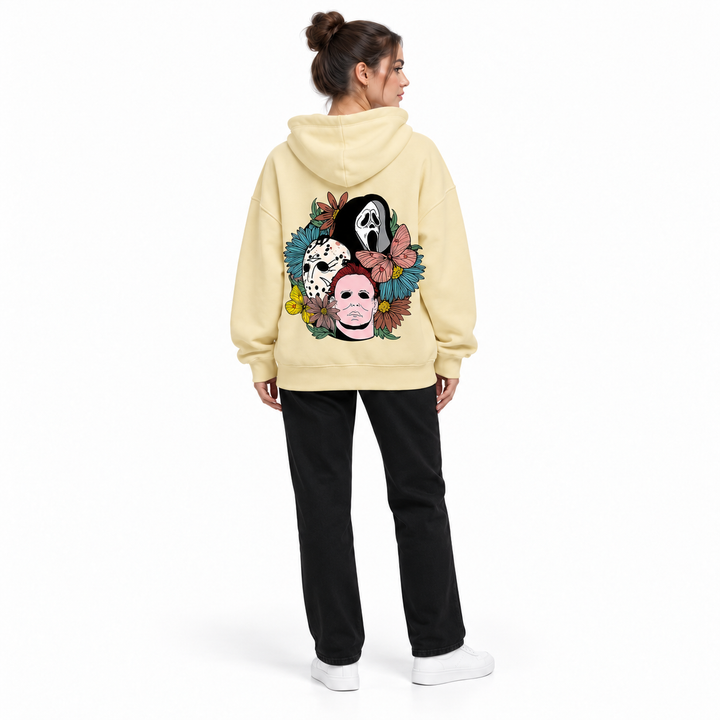 Full-body rear view of a woman wearing the apricot hooded pullover with a mask and flower print on a white studio background.