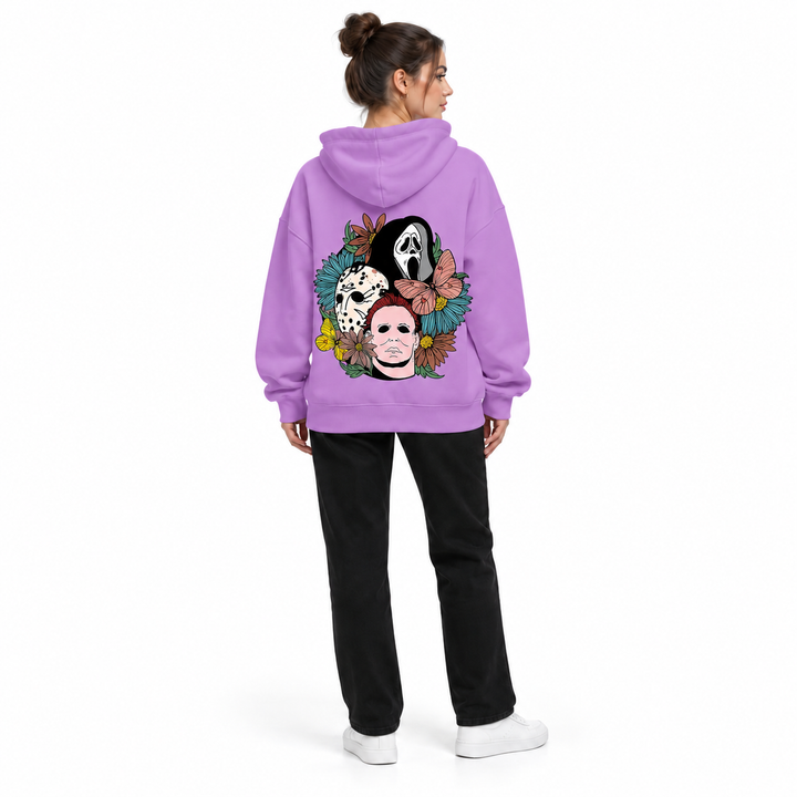 Full-body rear view of a woman wearing the purple hooded pullover with a floral mask back print on a white studio background.