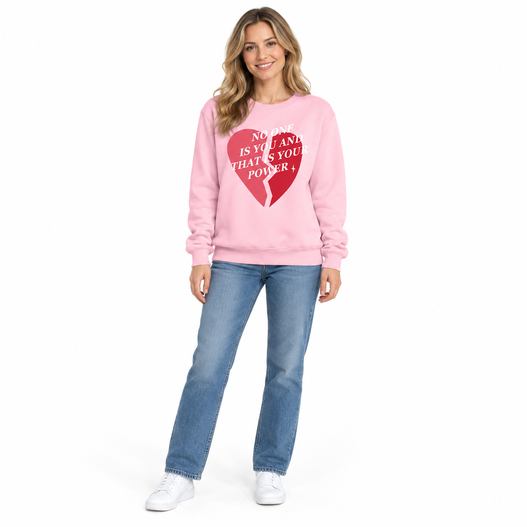 Pink printed sweatshirt on a full-length female model with blue jeans and white trainers, posed against plain white backdrop.