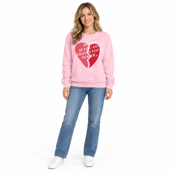 Pink printed sweatshirt on a full-length female model with blue jeans and white trainers, posed against plain white backdrop.
