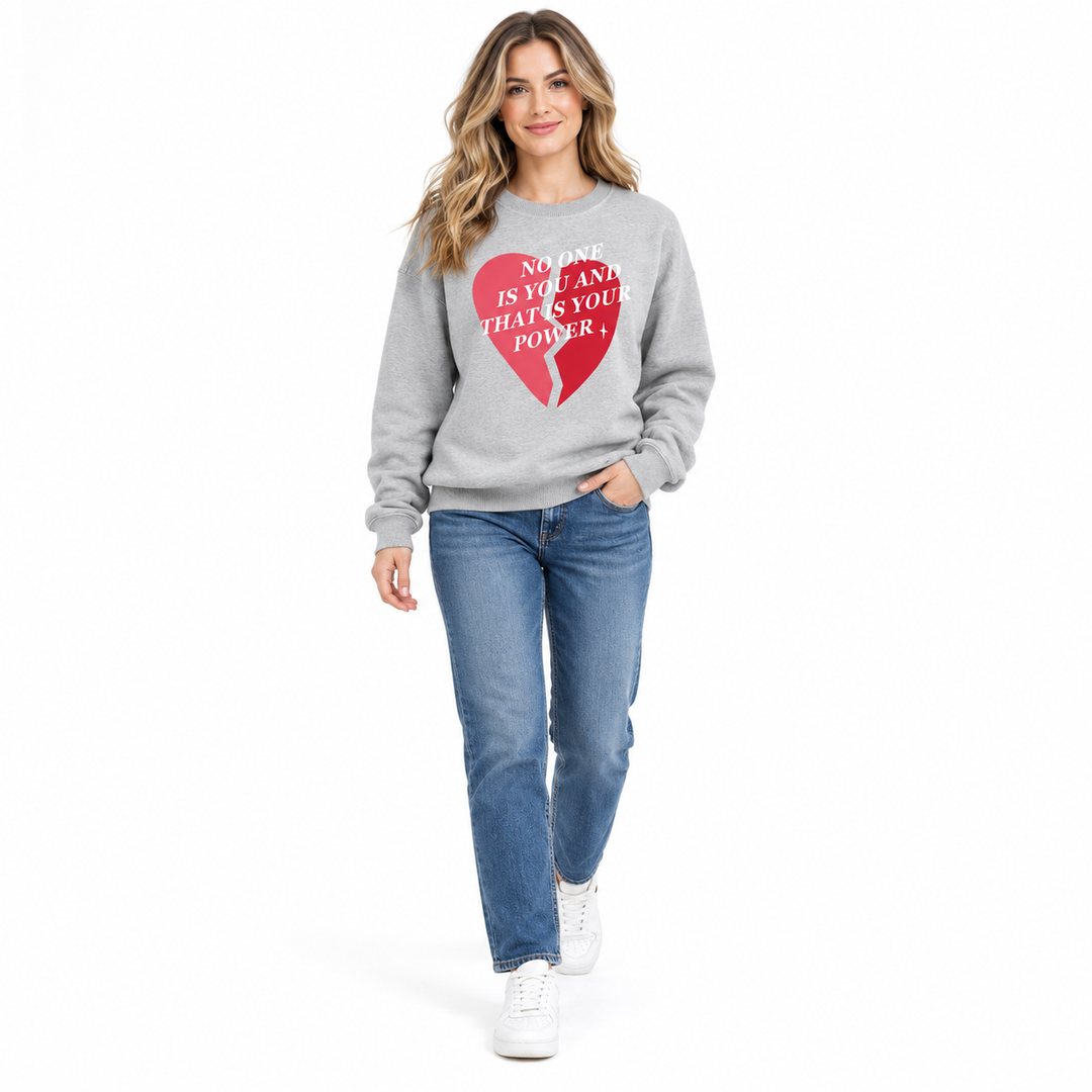 Gray printed sweatshirt on a full-length female model stepping forward in jeans and trainers against a white studio backdrop.
