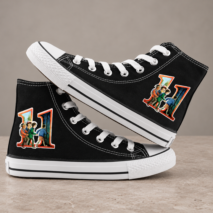 Black high-top sneakers, design 2, with the original side graphic on a warm gray studio background
