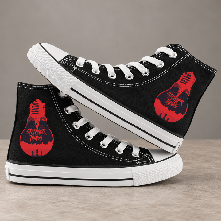 Black high-top sneakers, design 4, with the original side graphic on a warm gray studio background