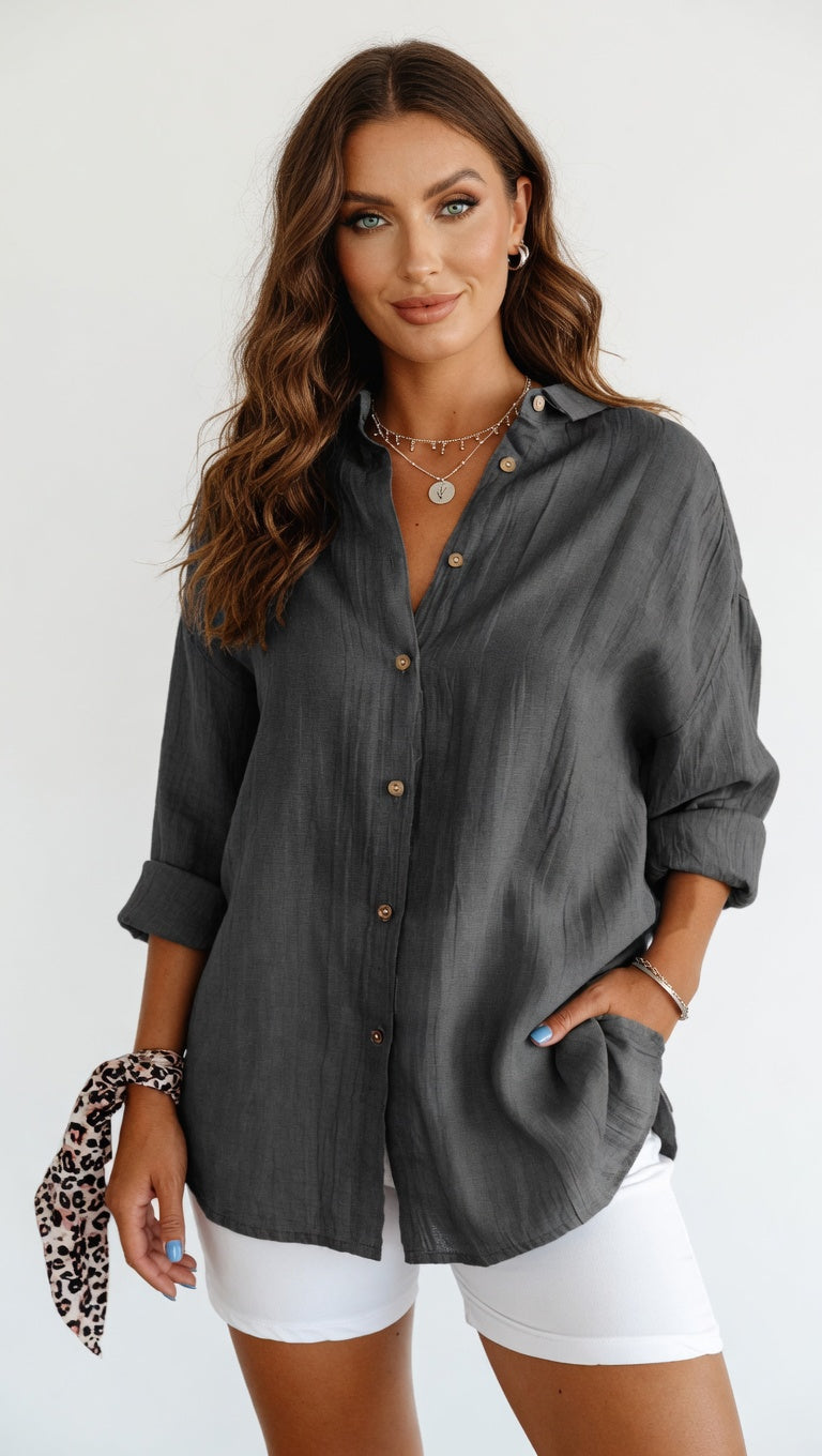 Woman wearing a gray button-up shirt and white shorts on a white background