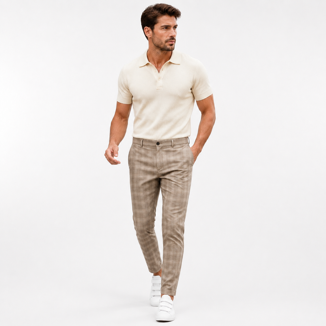 Khaki plaid trousers on an adult male model in a clean bright white studio walking pose with a cream polo and white sneakers.