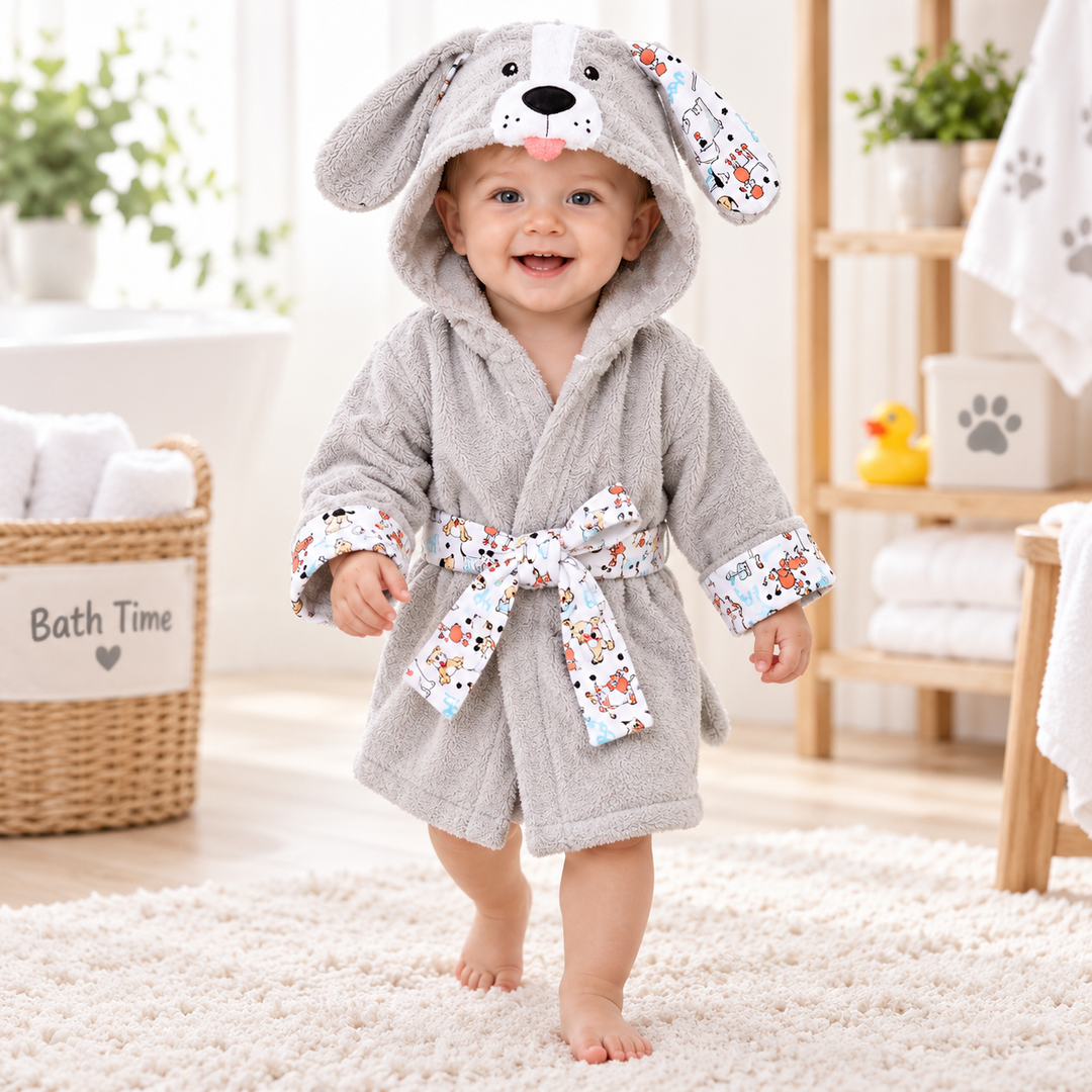 Child wearing the light gray puppy hooded kids bathrobe in a bathroom setting, showing the printed trim and tied waist belt.
