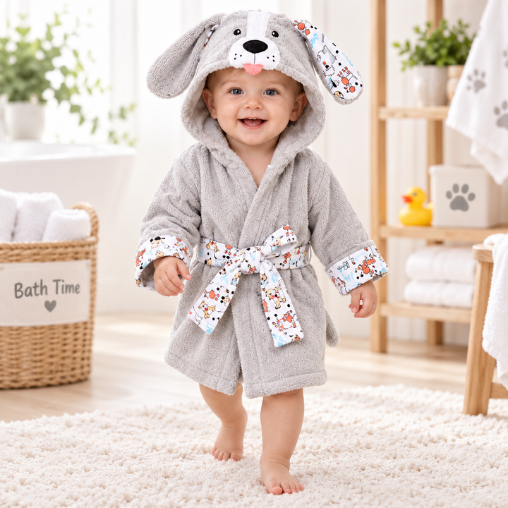 Child wearing the light gray puppy hooded kids bathrobe in a bathroom setting, showing the printed trim and tied waist belt.