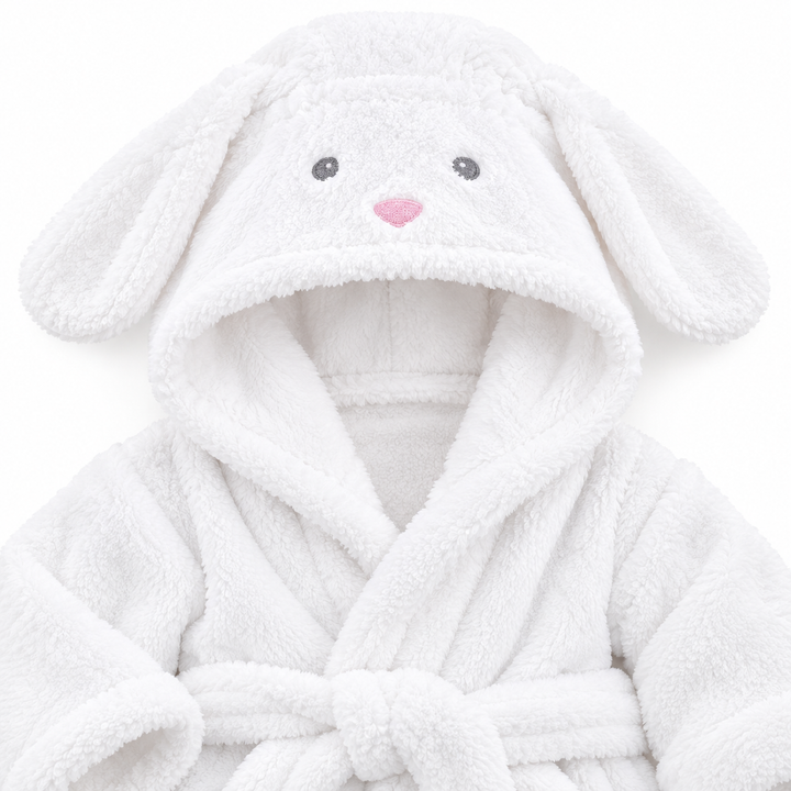 Close-up of a white animal hooded kids bathrobe showing the long ears, wrap front, waist belt and textured cotton surface.