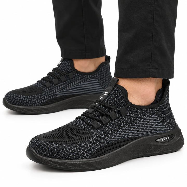 Black Style 1 knit work shoes worn with black trousers, shown close up.