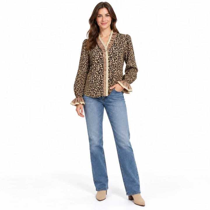 Wild Leopard Elegance blouse with beige ruffles, shown on a brunette model wearing blue jeans and neutral shoes in the studio