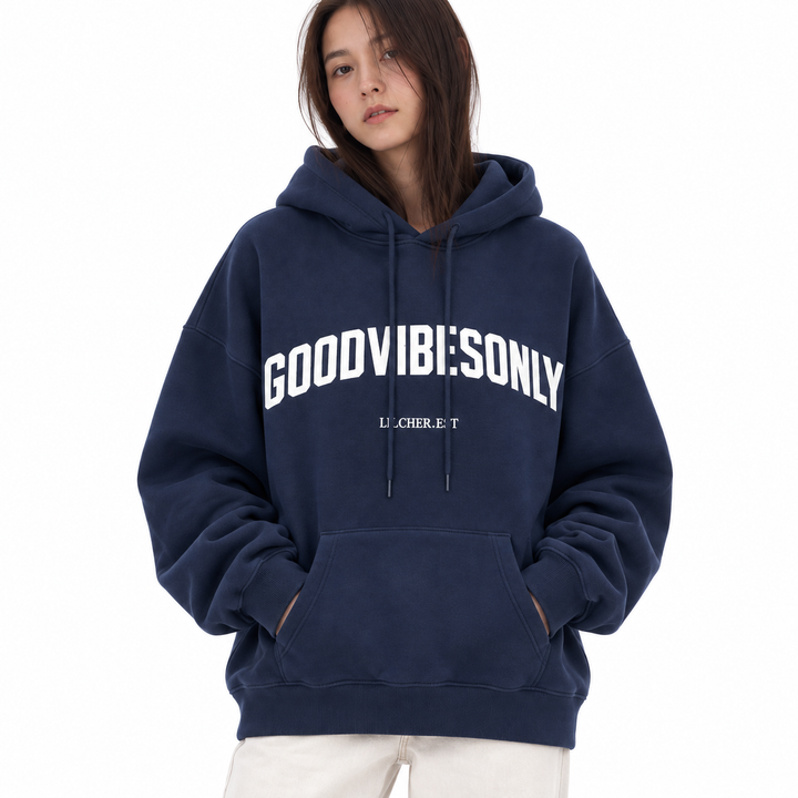 Navy blue hoodie front detail on the model, showing the kangaroo pocket, ribbed cuffs, drawstrings and white chest lettering.