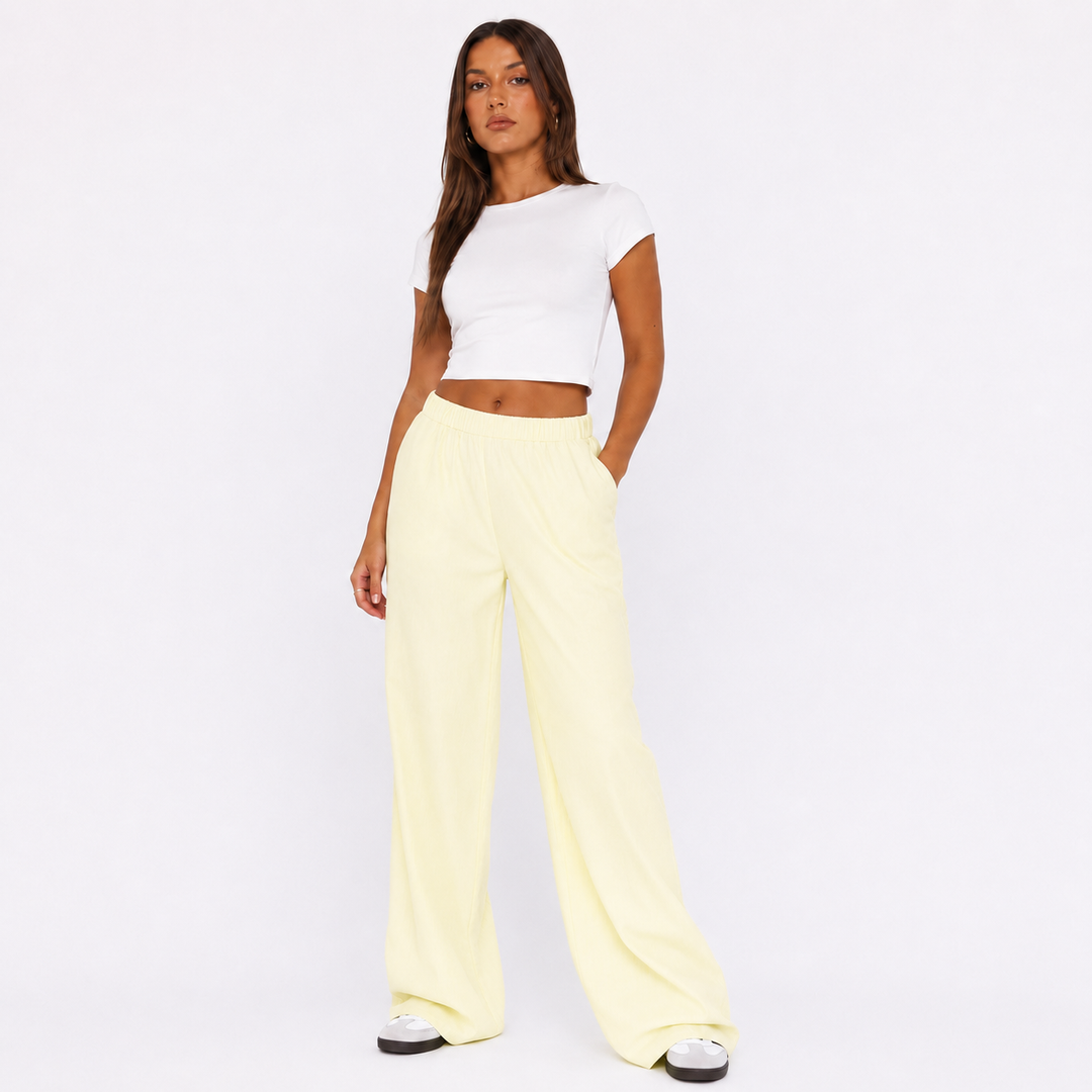 Light yellow wide leg pants for women on a studio model, showing elastic waist, side pocket area and relaxed summer silhouette.