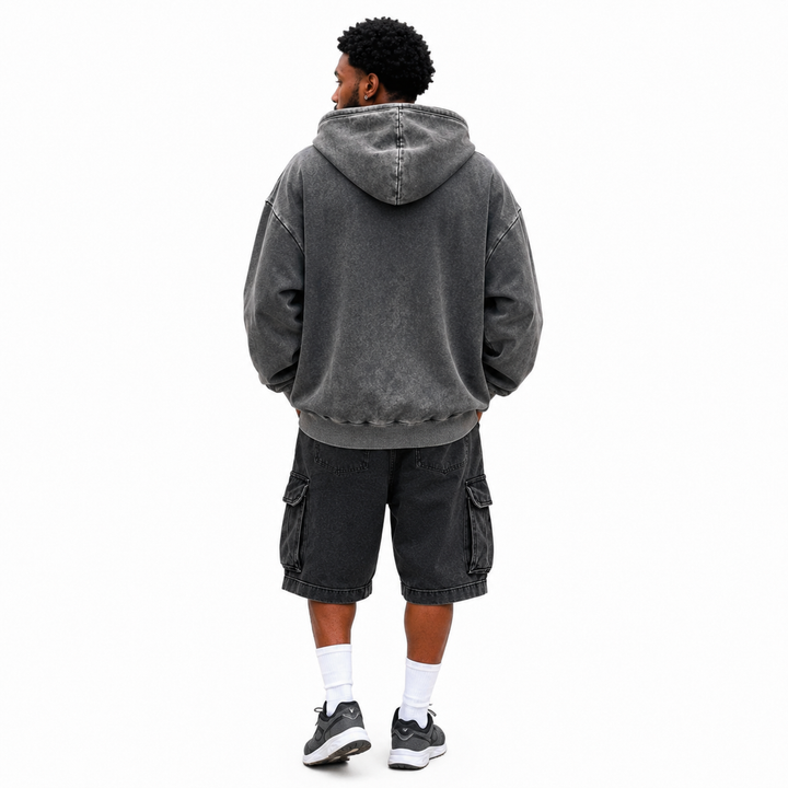 Back view of washed charcoal hoodie on male model showing hood, loose shape, dropped shoulders and ribbed lower hem on white.