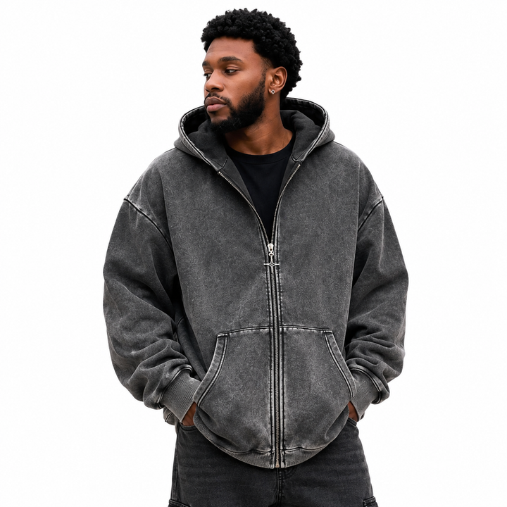 Hero view of washed charcoal zip hoodie on male model with zipper, hood, front pockets and ribbed trim on clean white studio.