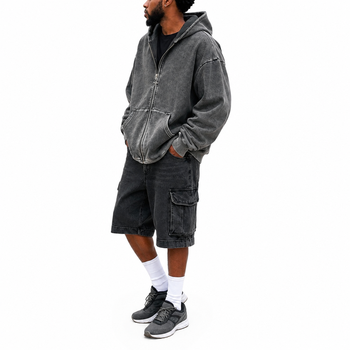 Side view of washed charcoal hoodie on male model showing relaxed shape, dropped shoulders, zipper and front pocket on white.