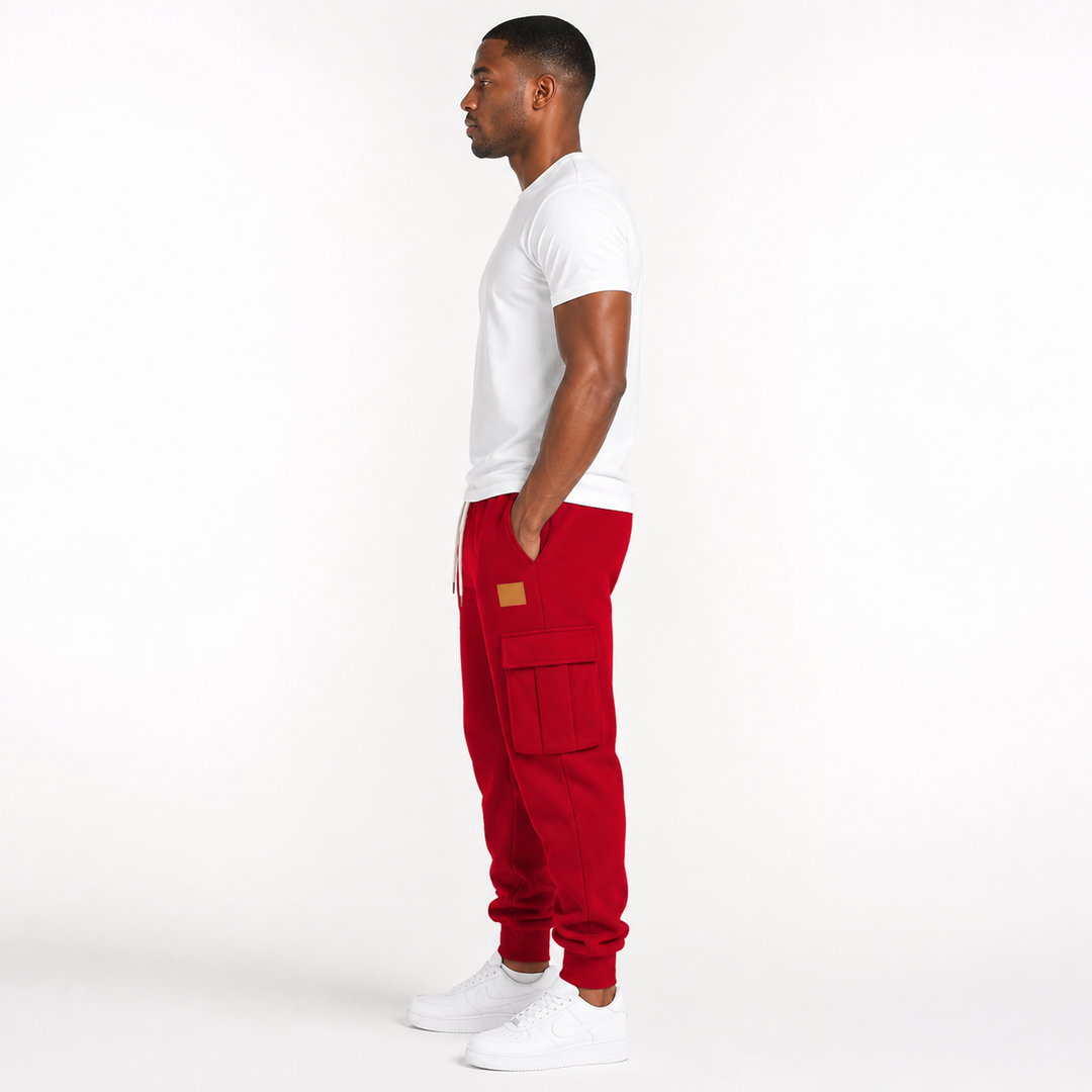 Male model wearing red cargo jogger pants in a full side view on a clean white studio background.