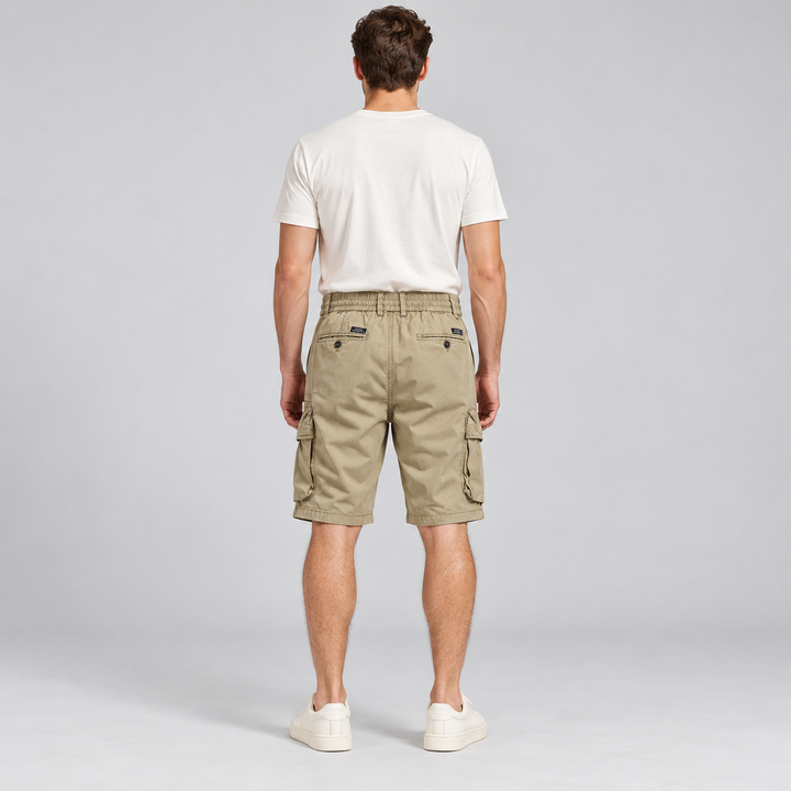 Back view of khaki cargo shorts with two buttoned rear pockets on a full-body model.