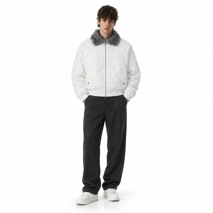 Male model wearing a white padded bomber jacket with a grey faux fur collar, dark wide-leg trousers and white shoes in studio