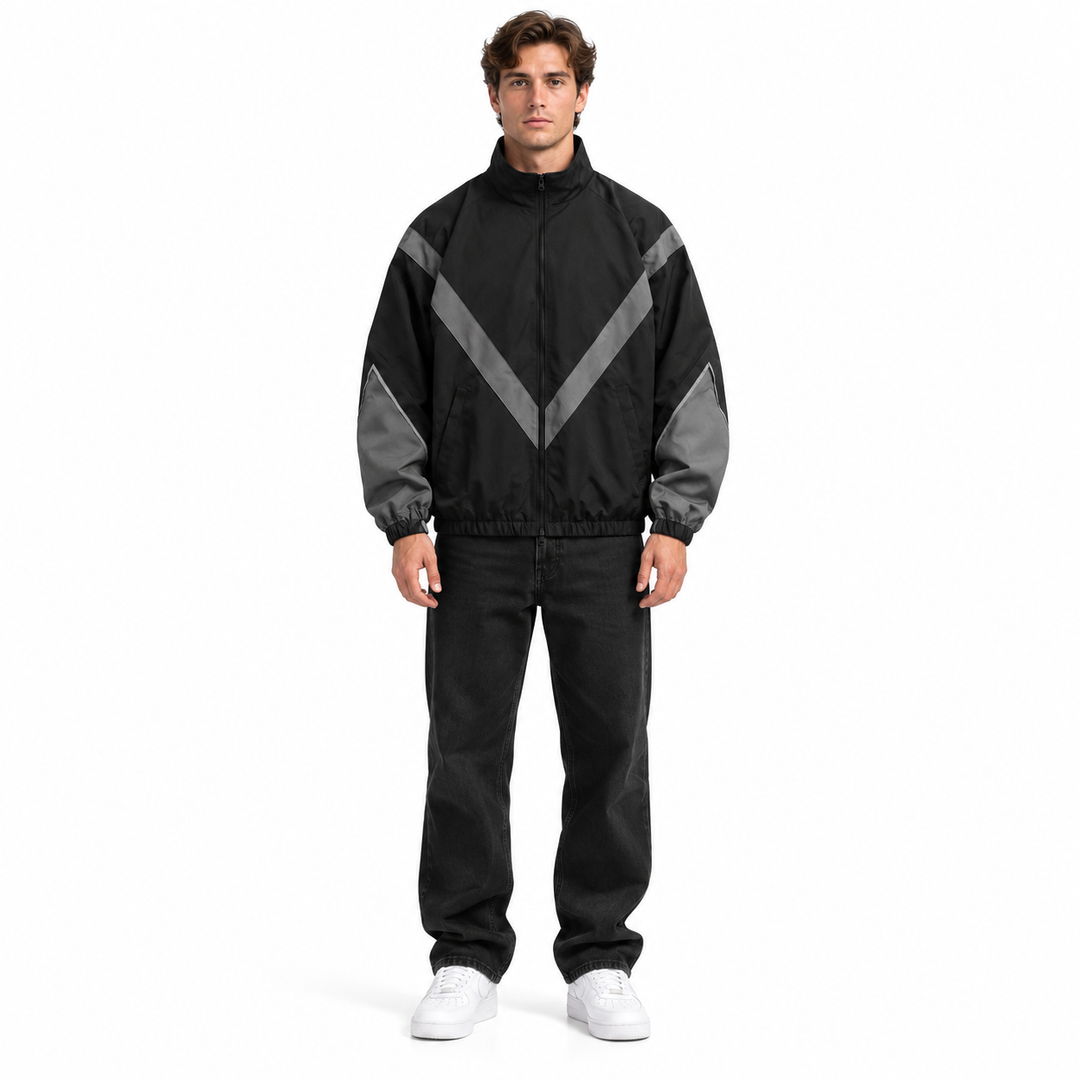 Front view of a male model in the black and gray style 6618 jacket with stand collar, chevron panels and front zip, on white.