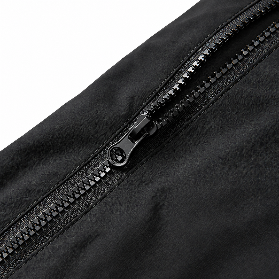 Close view of the black jacket zipper and surrounding fabric showing the metal slider and zipper teeth without supplier text.