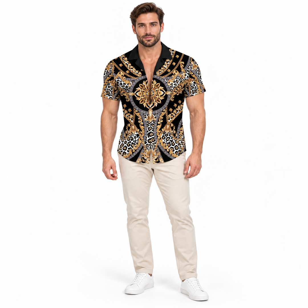 Male model wearing the black and gold ornamental shirt with beige trousers and white shoes against a white studio background.