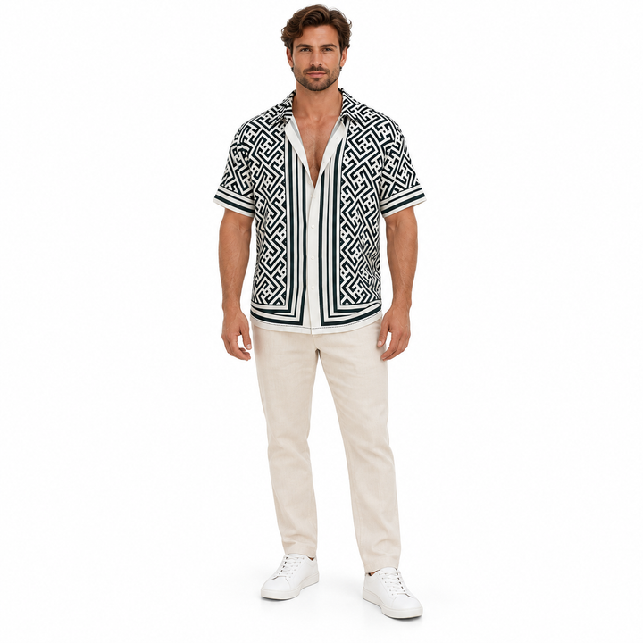 Male model wearing the black and white geometric shirt with beige trousers and white shoes against a white studio background.