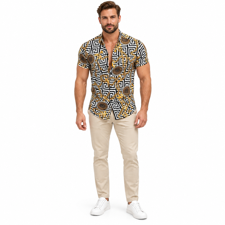 Male model wearing the black white and gold geometric short sleeve shirt in beige trousers and white shoes in a white studio.