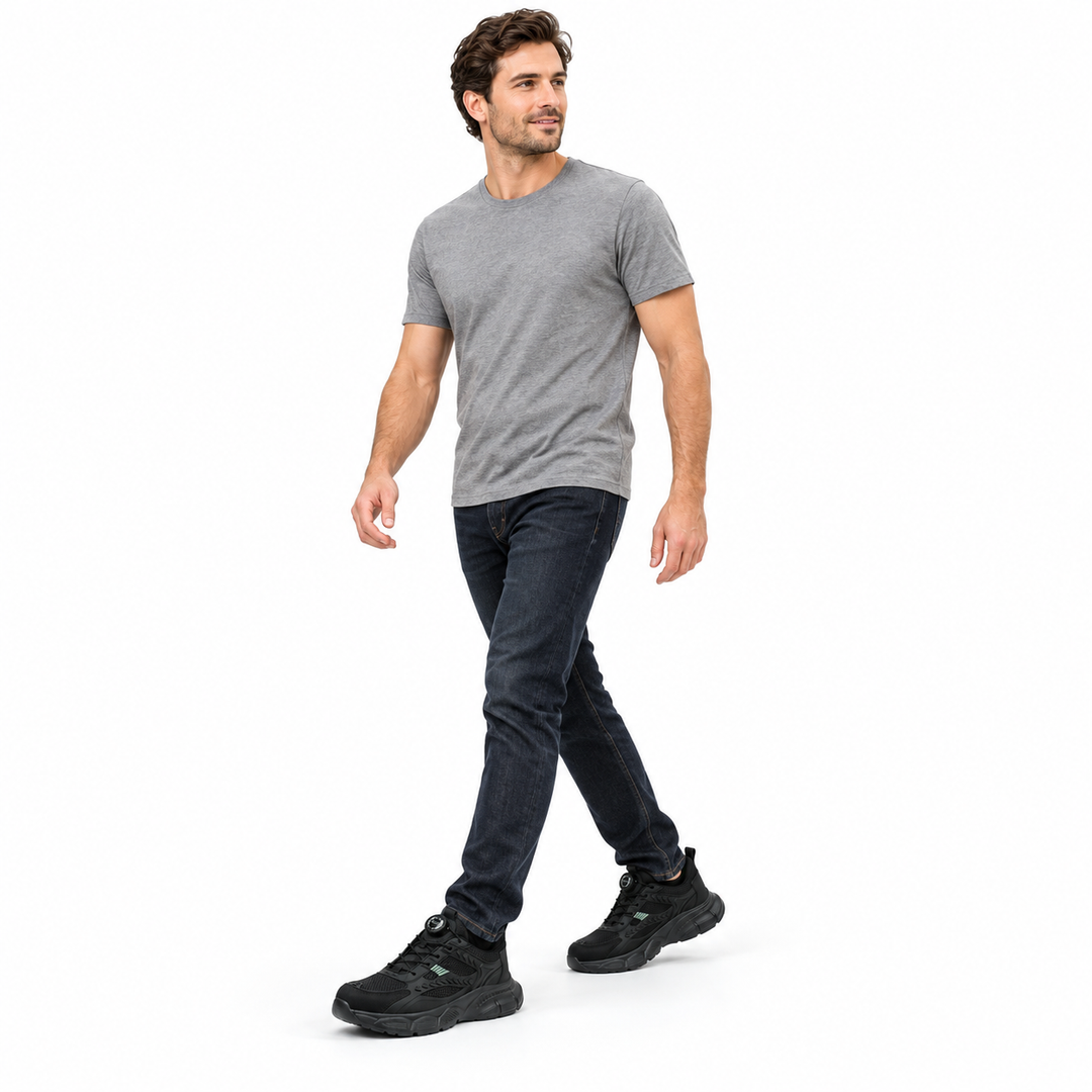 Adult male model in grey T-shirt and dark jeans wearing black model 9233 shoes shown full length against a white studio wall.