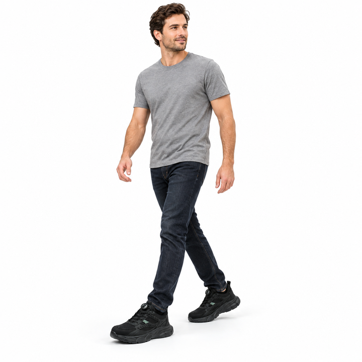 Adult male model in grey T-shirt and dark jeans wearing black model 9233 shoes shown full length against a white studio wall.