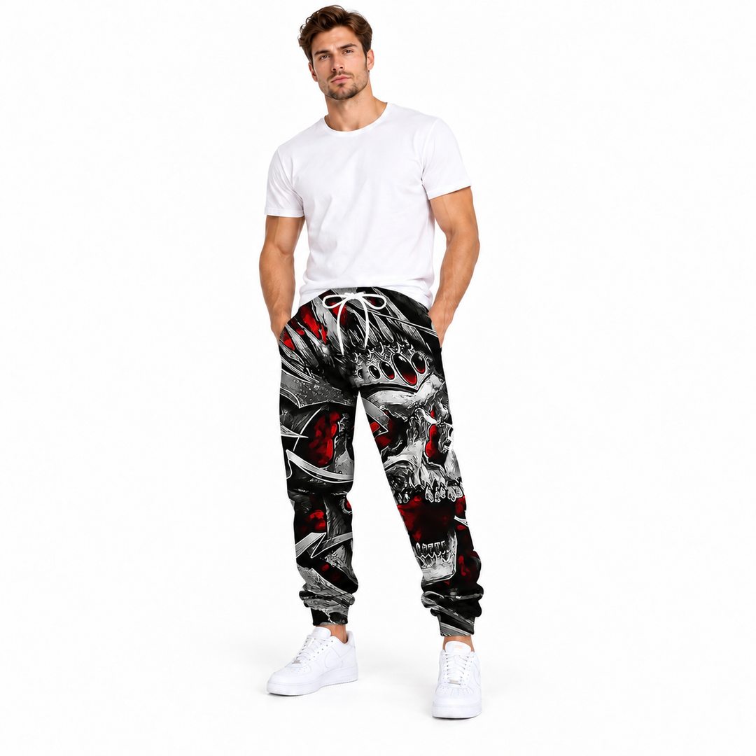 Male model wearing black red crown skull printed pants, with a white T-shirt and white sneakers, on a plain white background.