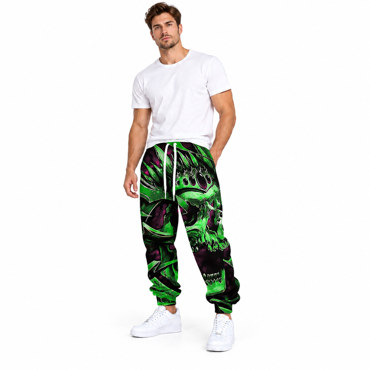 Male model wearing green crown skull drawstring pants, with a plain white tee and white sneakers, in a full-body studio view.