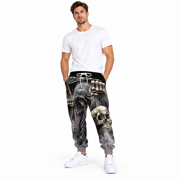 Male model wearing gray skull and fist printed pants, with a white tee and white sneakers, against a white studio background.