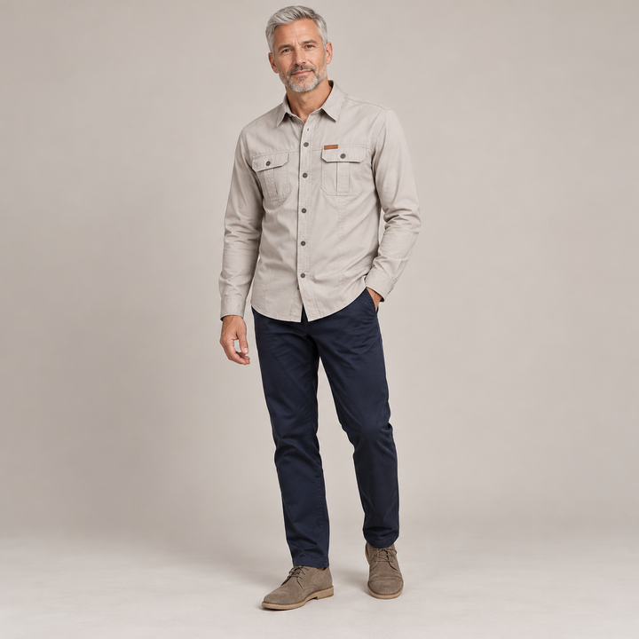 Beige long-sleeve utility shirt on a full-body model with grey hair.