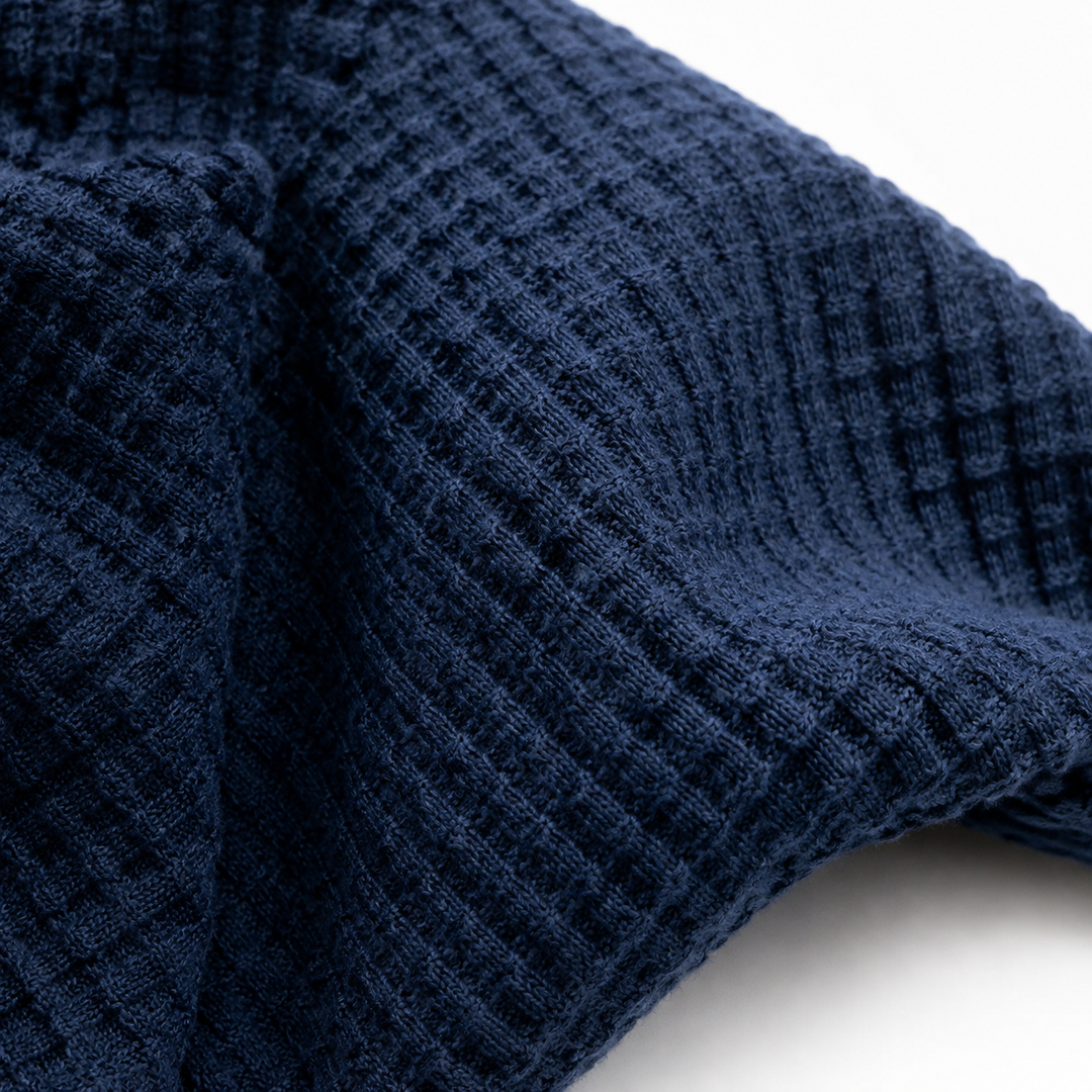 Navy waffle knit fabric macro showing the raised textured weave in detail.